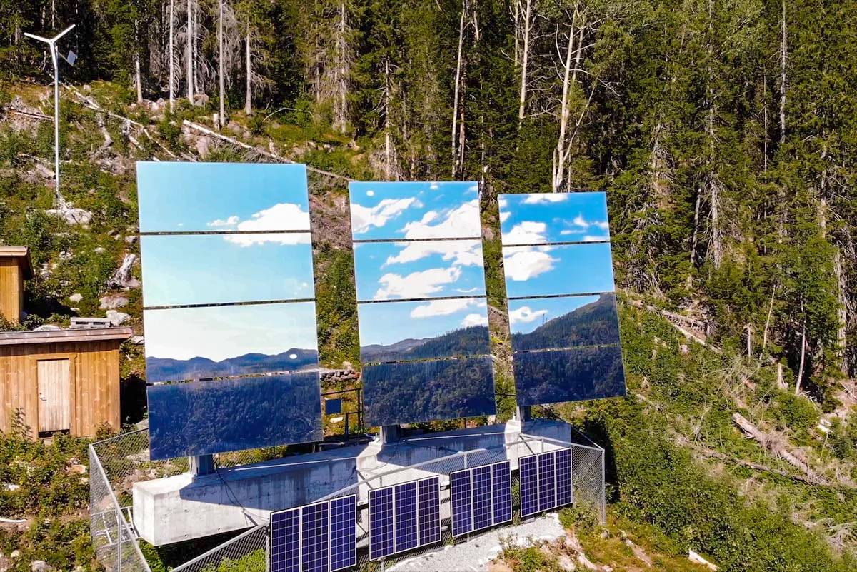 Tre gigantiske solspeil på fjellsiden over Rjukan med solcellepaneler nedenfor