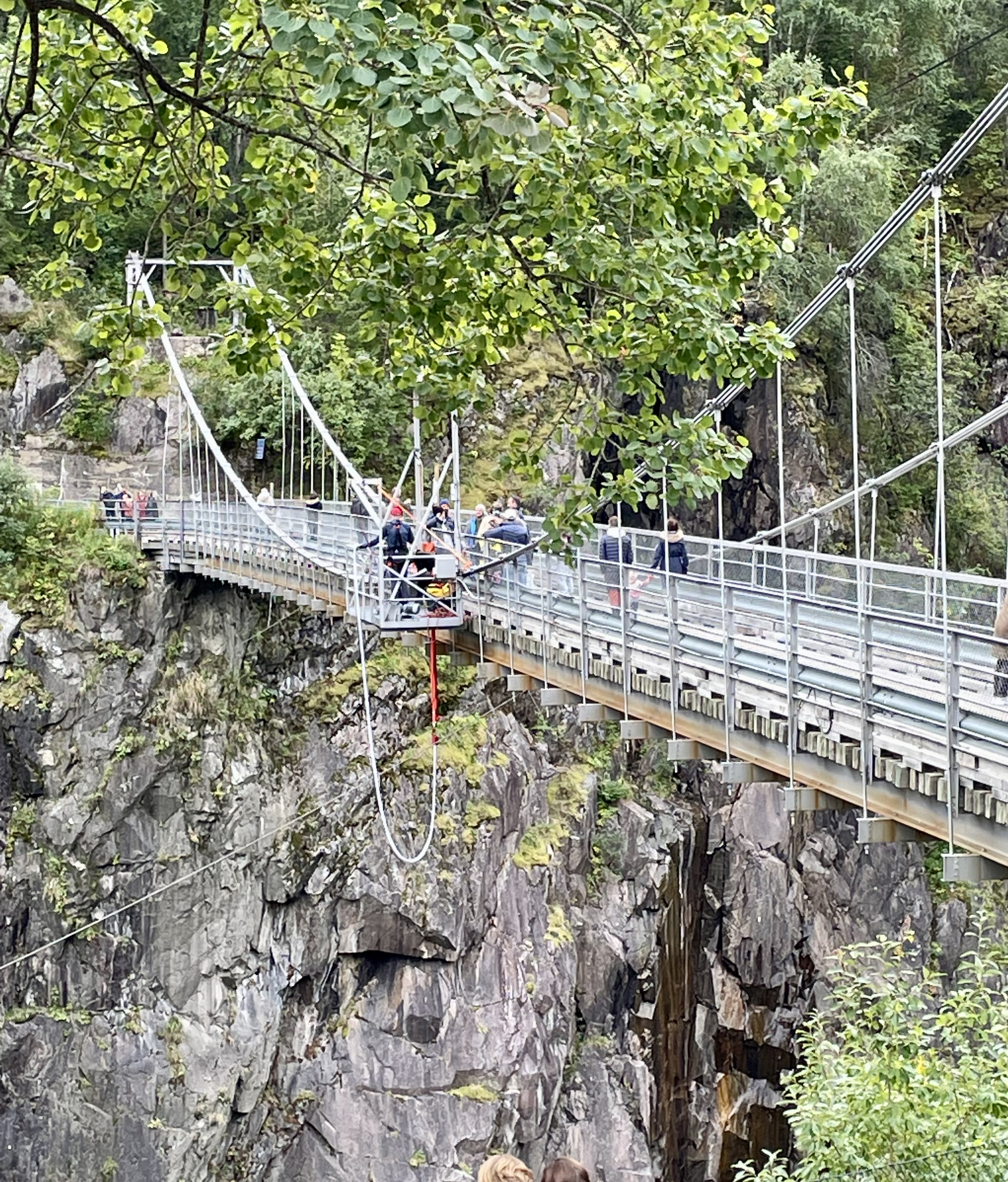 The suspension bridge at Vemork stretching across the deep gorge with visitors crossing it