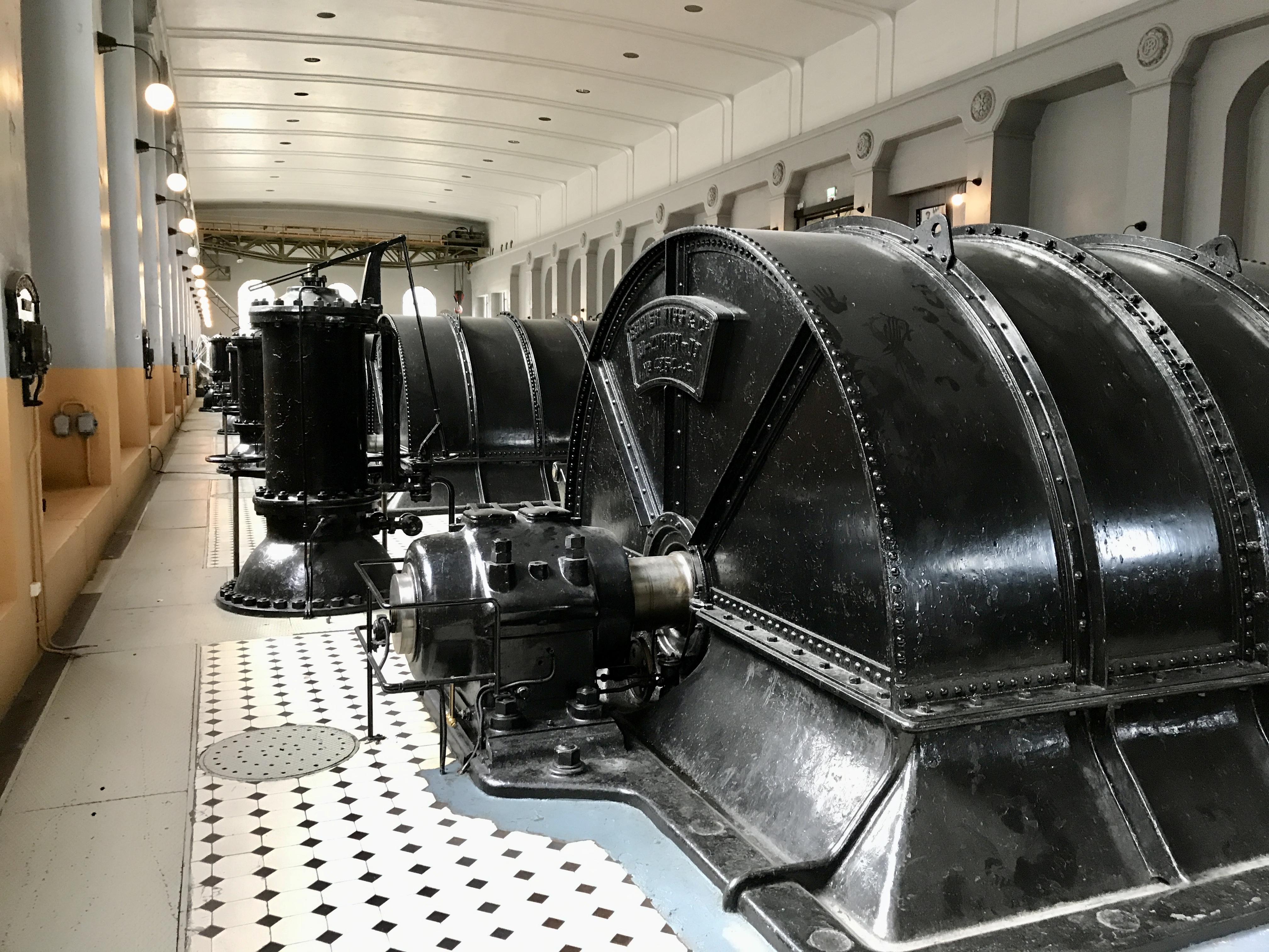 The monumental turbine hall at Vemork with black generators on a checkered tile floor